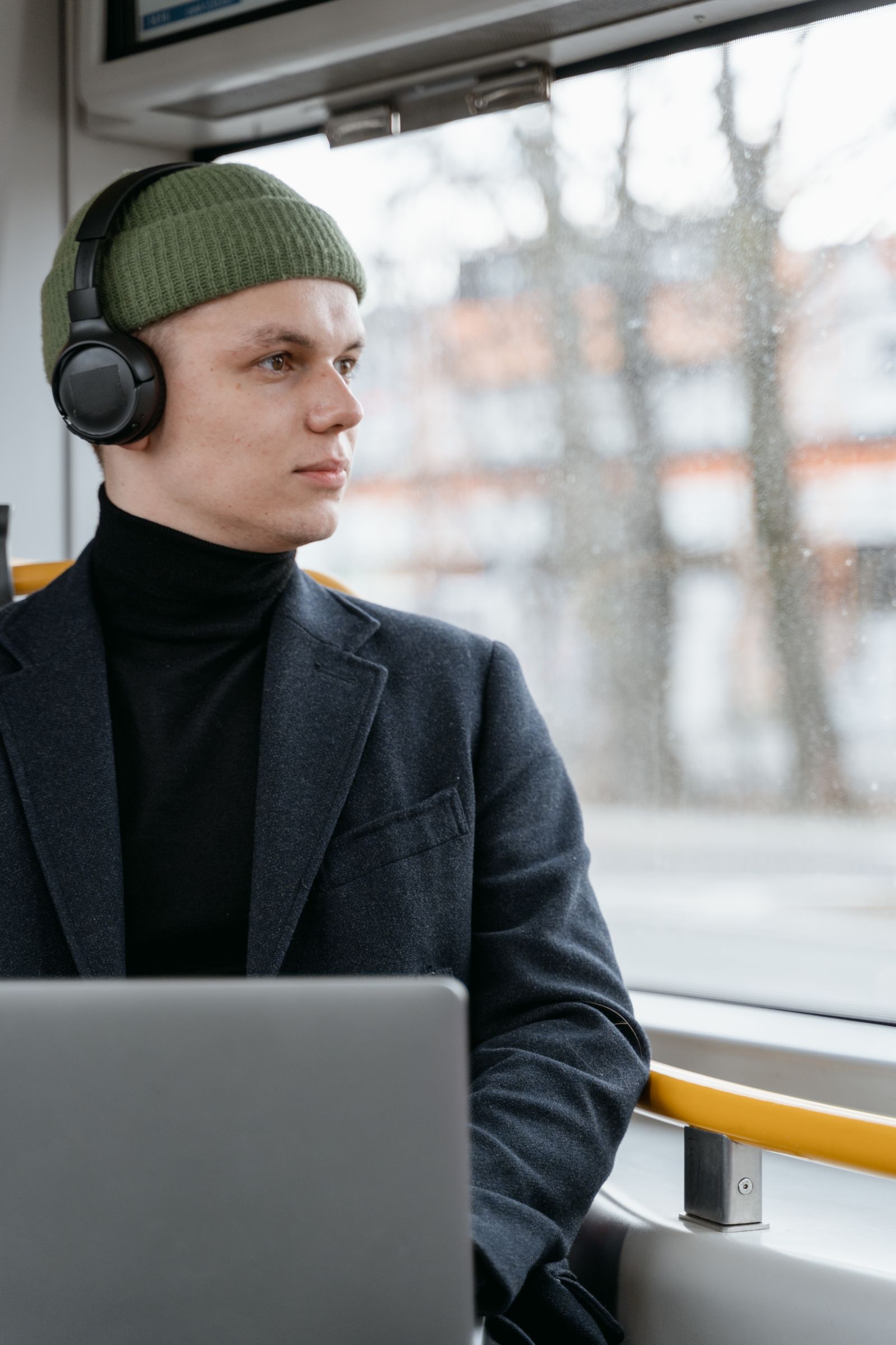 Commuter wearing over-ear headphones by a train window